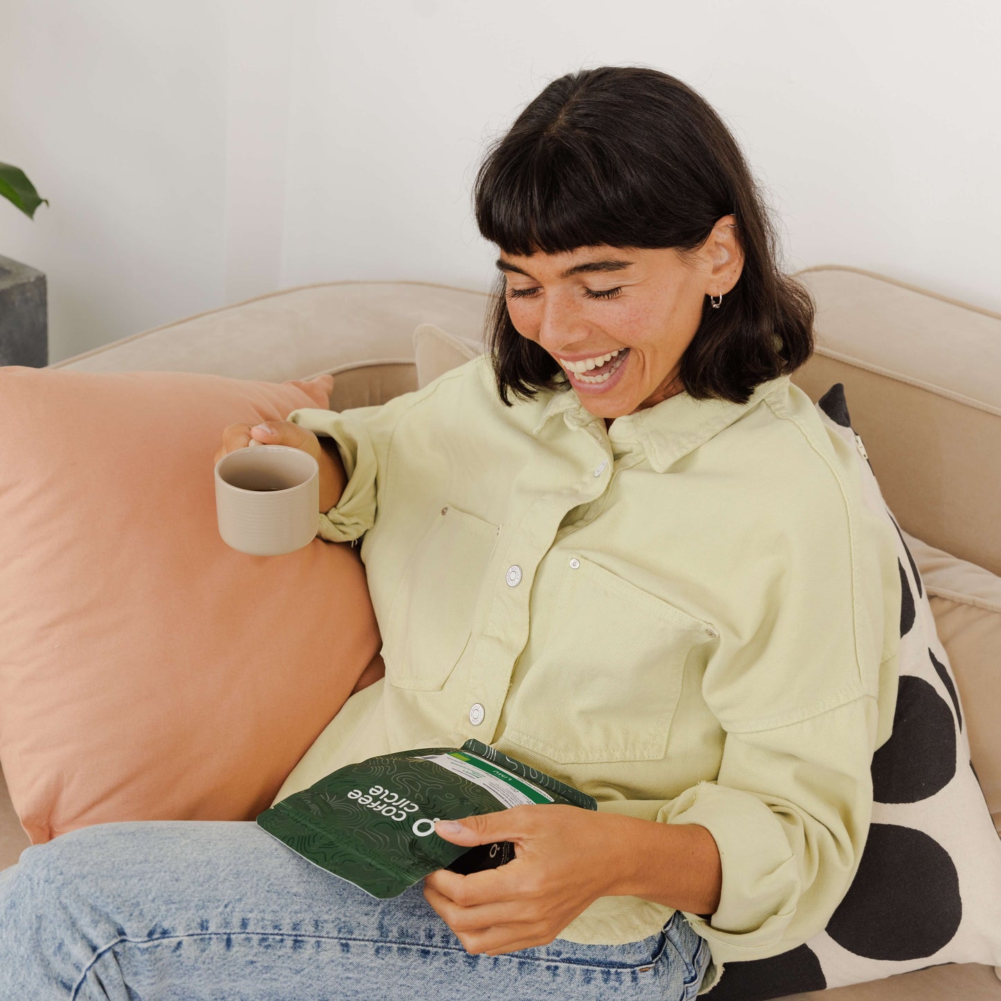 Frau entspannt mit Kaffee aus dem nachhaltigen Geschenkabo von Coffee Circle auf dem Sofa.